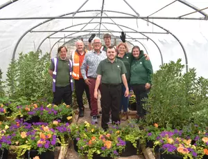 Cllr Hawkins and Representatives from Veolia and Newlands Bishop Farm stand amongst hanging baskets