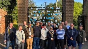 The Mayor of Solihull with employees from Veolia, Solihull Council and members of Men's Walking and Talking group standing in front of Malvern Gates. The gates are covered with blue hearts which have positive messages written on them for people struggling with mental health